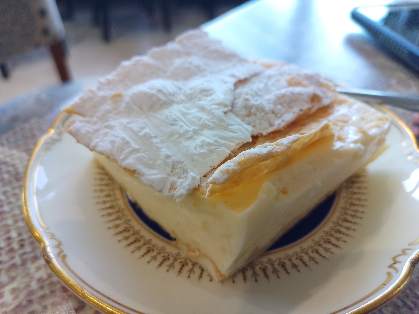 A square of vanilla custard cake on a gold rimmed plate at the Good Heart Cafe